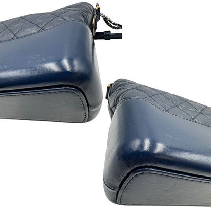 Angoli di una borsa Chanel Gabrielle in pelle matelassé blu navy con parti metalliche dorate e argentate. Munita di una tracolla in catena e pelle intrecciata con spallaccio. Tirante delle cerniera impreziosito dall'iconico logo CC in metallo dorato, completa di corredo.
