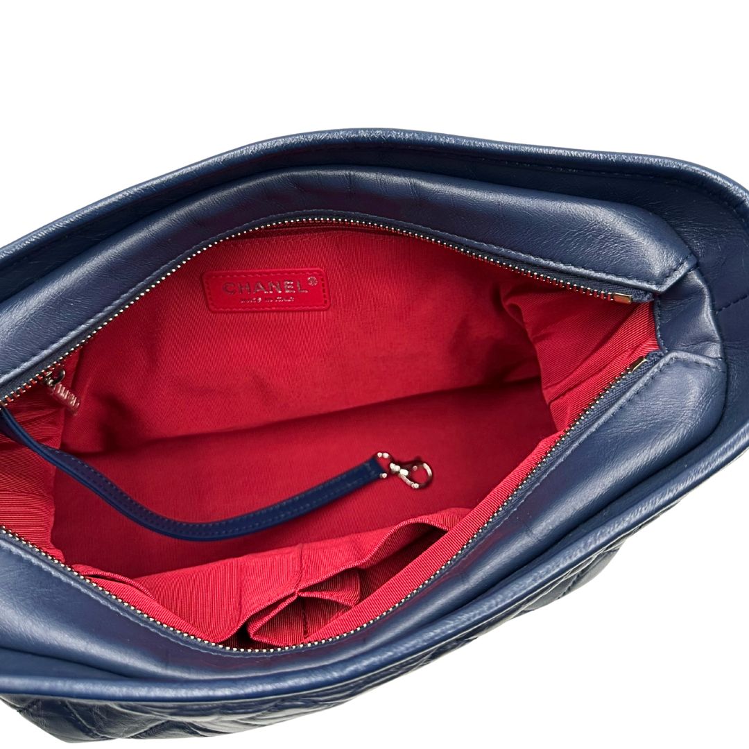 Interno di una borsa Chanel Gabrielle in pelle matelassé blu navy con parti metalliche dorate e argentate. Munita di una tracolla in catena e pelle intrecciata con spallaccio. Tirante delle cerniera impreziosito dall'iconico logo CC in metallo dorato, completa di corredo.