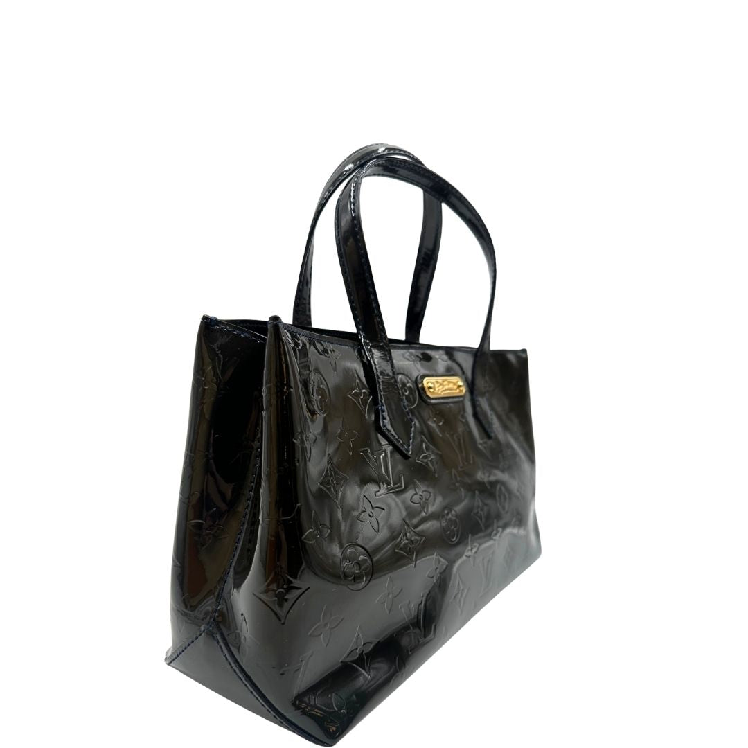 lato Borsa Louis Vuitton in pelle verniciata marrone con riflessi che tendono al verde e parti metalliche dorate; munita di doppi manici, da portare a mano. Completa di corredo, di lusso, originale, ottime condizioni, usata.