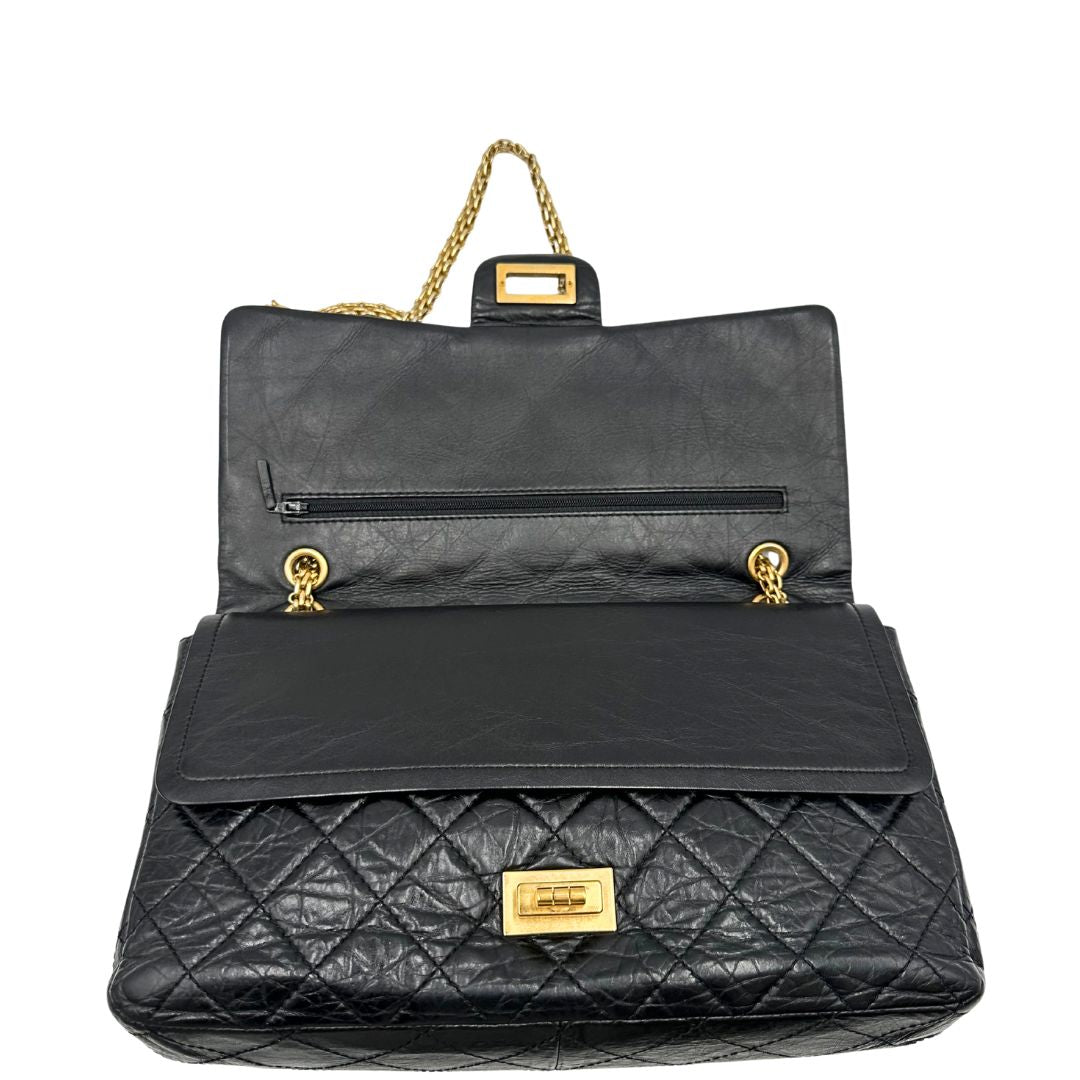 Apertura di una borsa Chanel 2.55 in pelle aged nera trapuntata, con parti metalliche dorate. Munita di una tracolla scorrevole in catena. Indossabile a spalla o a tracolla. Completa di scatola.