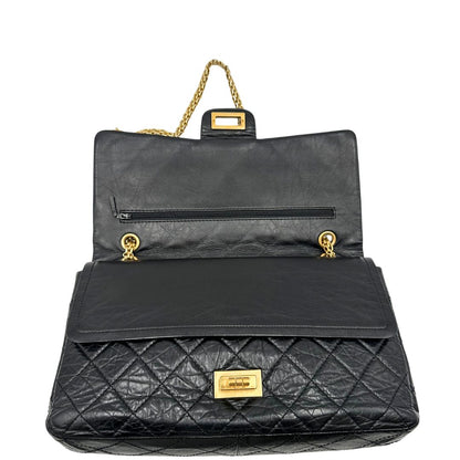 Apertura di una borsa Chanel 2.55 in pelle aged nera trapuntata, con parti metalliche dorate. Munita di una tracolla scorrevole in catena. Indossabile a spalla o a tracolla. Completa di scatola.