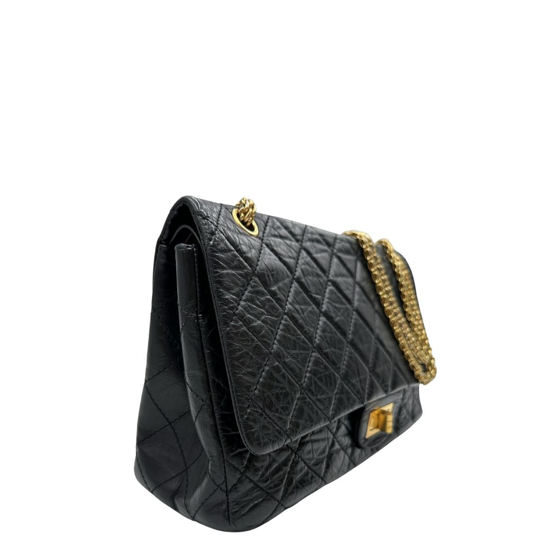 Laterale sinistro di una borsa Chanel 2.55 in pelle aged nera trapuntata, con parti metalliche dorate. Munita di una tracolla scorrevole in catena. Indossabile a spalla o a tracolla. Completa di scatola.