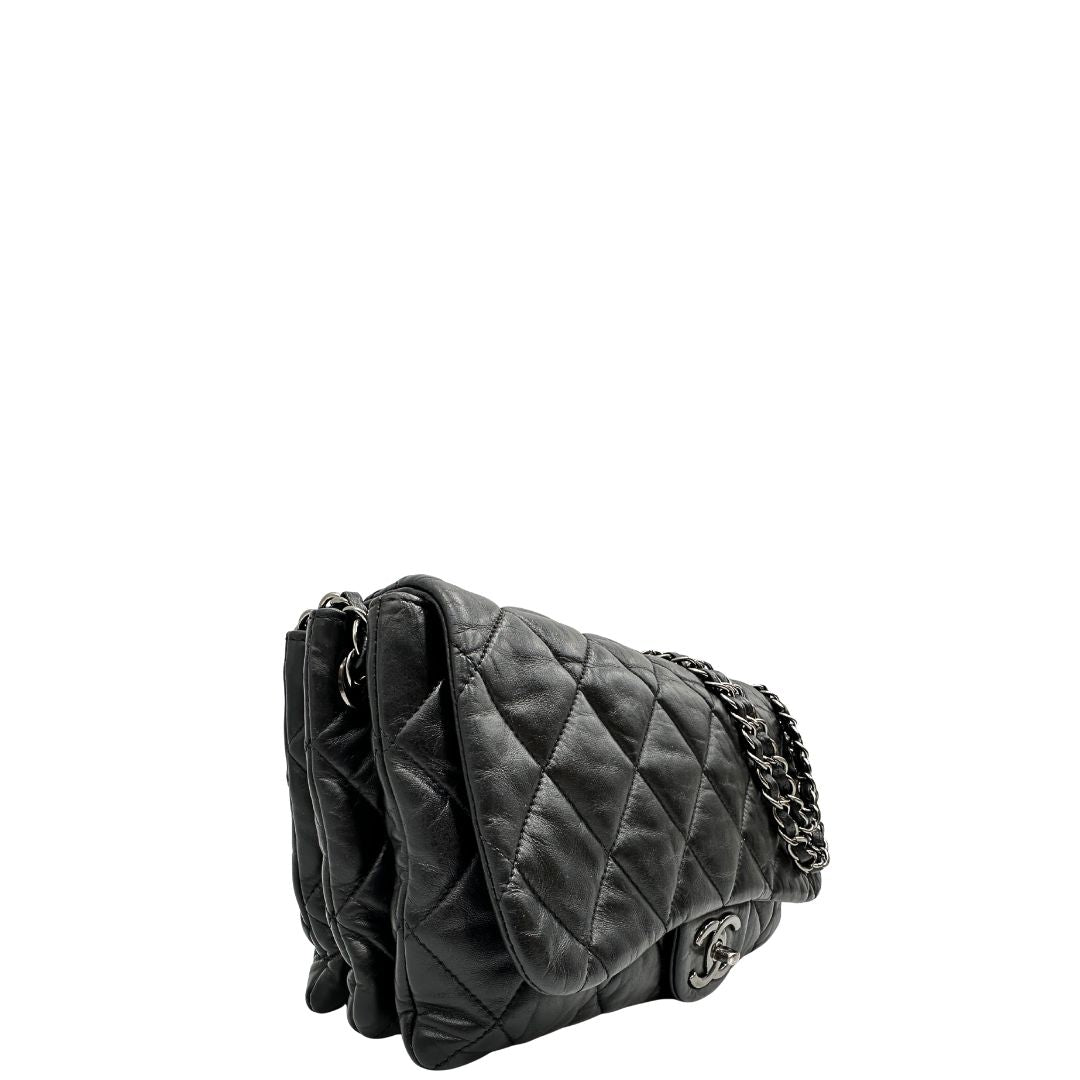 Lato destro di una Borsa Chanel in pelle nera matelassè e parti metalliche argentate; munita di una tracolla scorrevole in catena e pelle. Indossabile a spalla e a tracolla. Completa di scatola. Originale, usata, di lusso, in condizioni eccellenti.