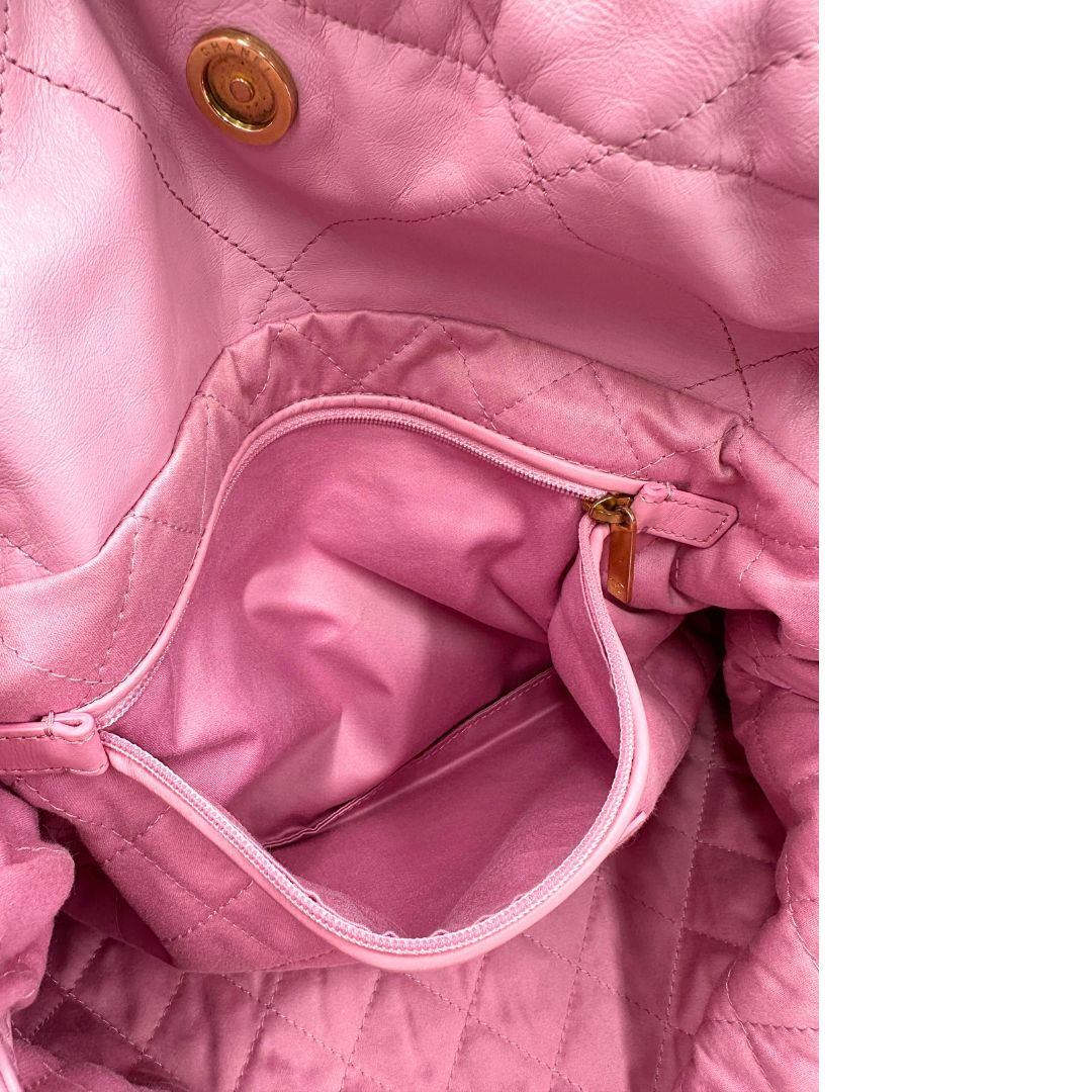 Interno di una borsa Chanel 22 in pelle trapuntata rosa con parti metalliche dorate; dotata di pochette estraibile e amovibile, doppi manici in catena e pelle per portarla a spalla. Chiusura con bottone automatici. Completa di scatola e dustbag.