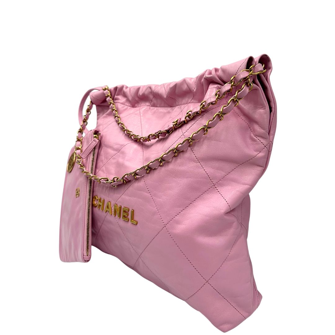 Laterale destro di una borsa Chanel 22 in pelle trapuntata rosa con parti metalliche dorate; dotata di pochette estraibile e amovibile, doppi manici in catena e pelle per portarla a spalla. Chiusura con bottone automatici. Completa di scatola e dustbag.