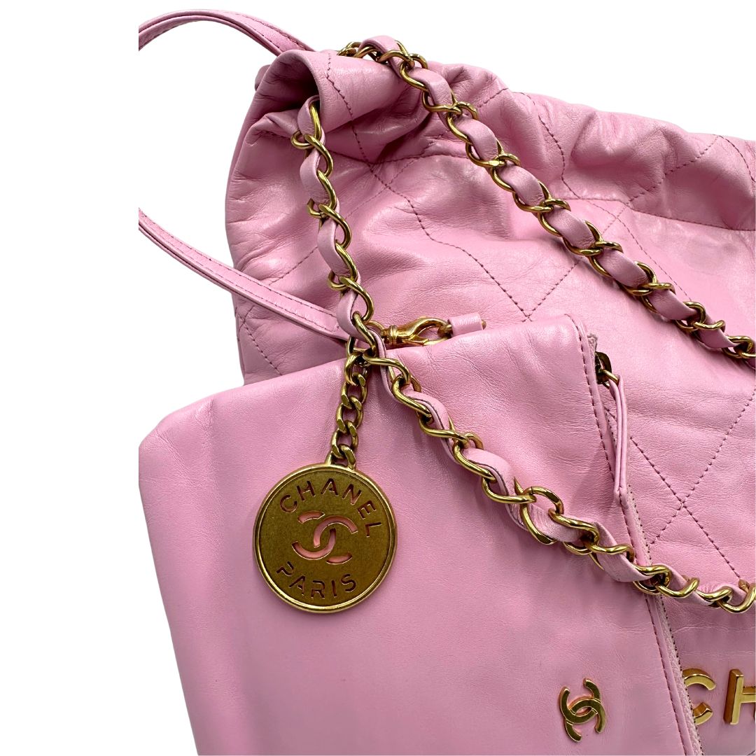 Medaglione di una borsa Chanel 22 in pelle trapuntata rosa con parti metalliche dorate; dotata di pochette estraibile e amovibile, doppi manici in catena e pelle per portarla a spalla. Chiusura con bottone automatici. Completa di scatola e dustbag.