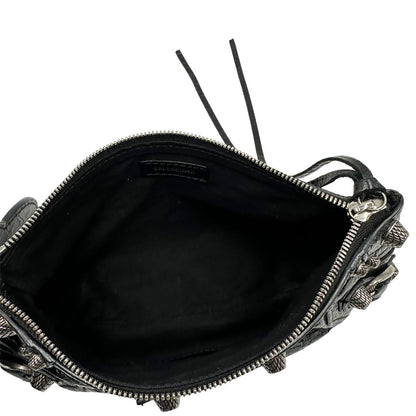 Interno di una pochette Balenciaga in pelle effetto invecchiato nera, con parti metalliche argentate; munita di uno specchietto a forma di cuore, polsino amovibile e un mini porta monete e carte. Completa di dustbag.