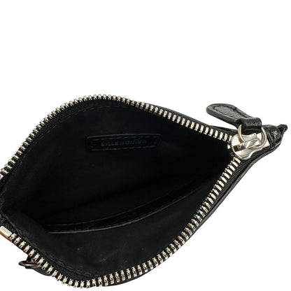 Interno di una pochette Balenciaga in pelle effetto invecchiato nera, con parti metalliche argentate; munita di uno specchietto a forma di cuore, polsino amovibile e un mini porta monete e carte. Completa di dustbag.