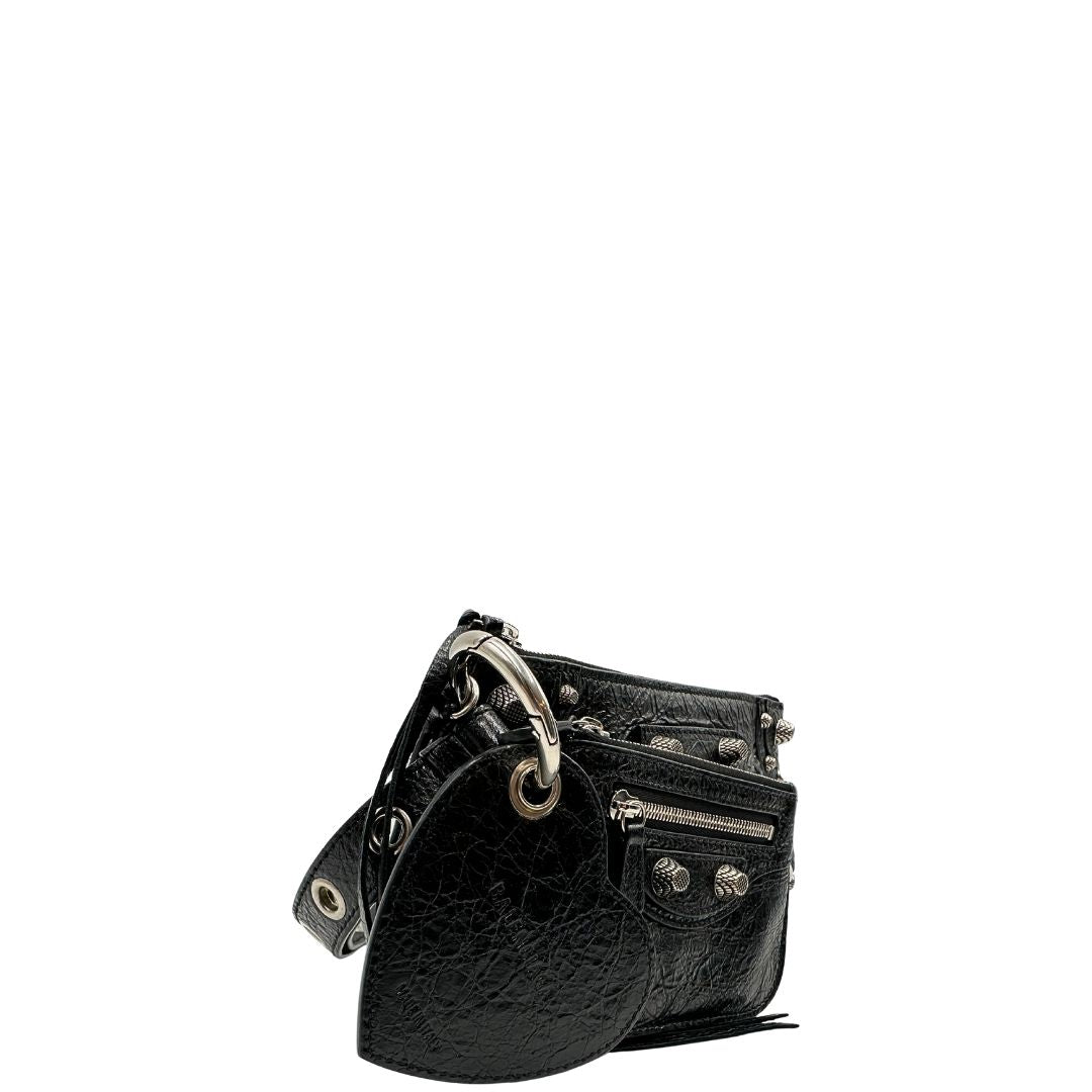 Laterale sinistro di una pochette Balenciaga in pelle effetto invecchiato nera, con parti metalliche argentate; munita di uno specchietto a forma di cuore, polsino amovibile e un mini porta monete e carte. Completa di dustbag.