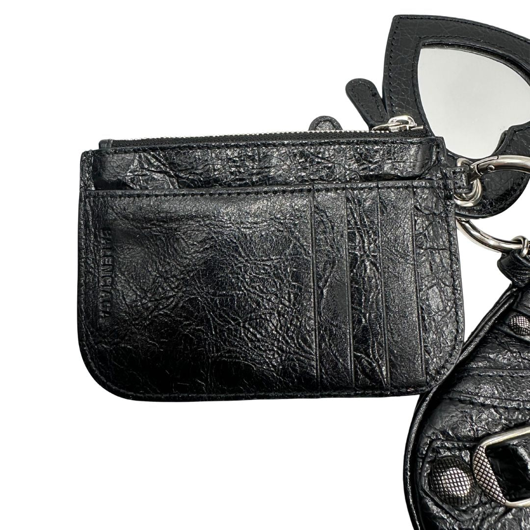 Porta monete e carte di una pochette Balenciaga in pelle effetto invecchiato nera, con parti metalliche argentate; munita di uno specchietto a forma di cuore e polsino amovibile. Completa di dustbag.