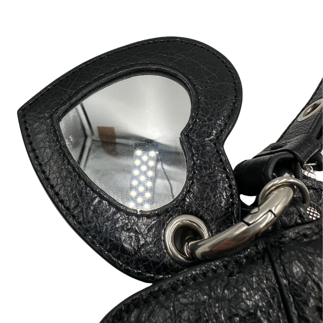 Specchietto a fora di cuore di una pochette Balenciaga in pelle effetto invecchiato nera, con parti metalliche argentate; munita di un polsino amovibile e un mini porta monete e carte. Completa di dustbag.