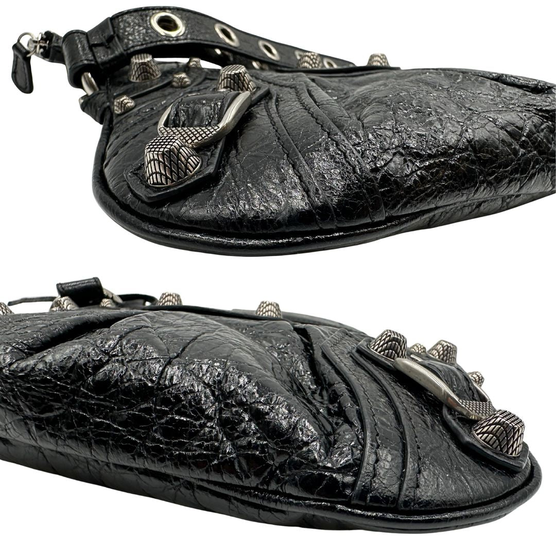 Angoli di una pochette Balenciaga in pelle effetto invecchiato nera, con parti metalliche argentate; munita di uno specchietto a forma di cuore, polsino amovibile e un mini porta monete e carte. Completa di dustbag.