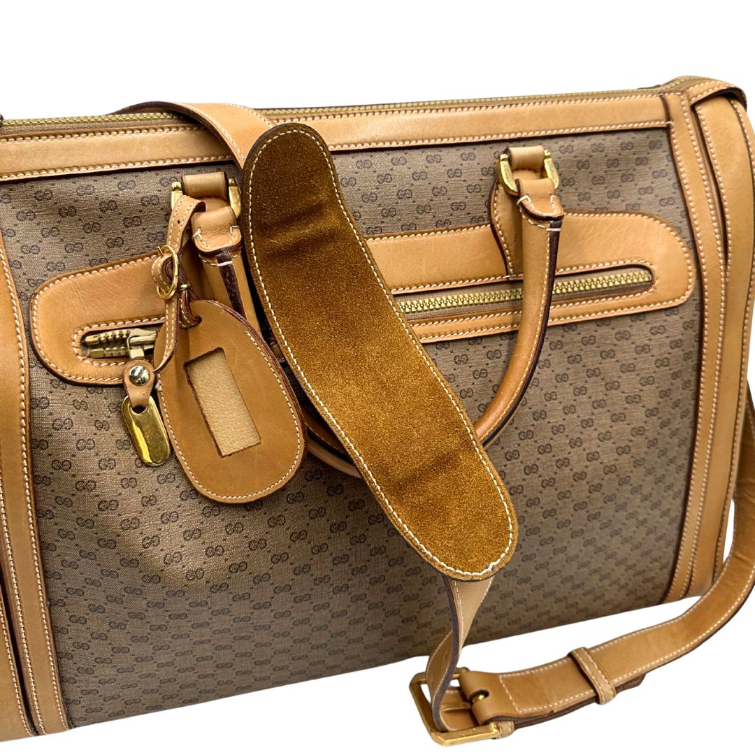 Dettaglio tracolla di una borsa Gucci in canvas beige GG con finiture in pelle color cammello e parti metalliche dorate, munita di doppi manici stondati e di una tracolla amovibile e regolabile. Dotata di tag porta address.