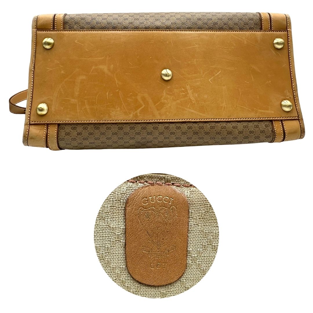 Base e logo di una borsa Gucci in canvas beige GG con finiture in pelle color cammello e parti metalliche dorate, munita di doppi manici stondati e di una tracolla amovibile e regolabile. Dotata di tag porta address.
