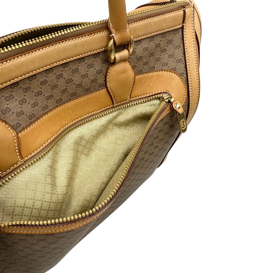 Tasca esterna di una borsa Gucci in canvas beige GG con finiture in pelle color cammello e parti metalliche dorate, munita di doppi manici stondati e di una tracolla amovibile e regolabile. Dotata di tag porta address.