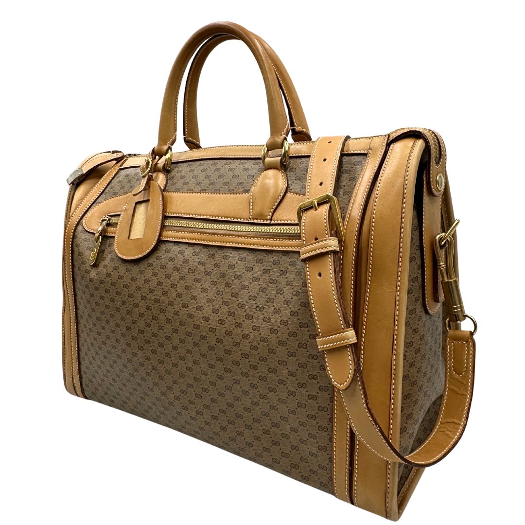 Laterale destro di una borsa Gucci in canvas beige GG con finiture in pelle color cammello e parti metalliche dorate, munita di doppi manici stondati e di una tracolla amovibile e regolabile. Dotata di tag porta address.