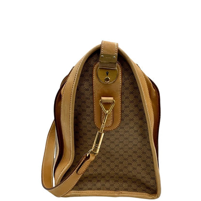 Laterale di una borsa Gucci in canvas beige GG con finiture in pelle color cammello e parti metalliche dorate, munita di doppi manici stondati e di una tracolla amovibile e regolabile. Dotata di tag porta address.