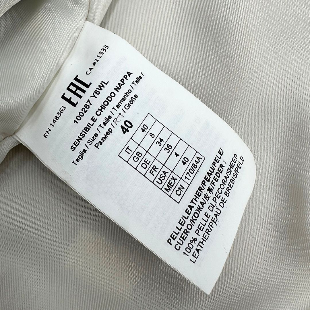 Etichetta di una giacca in 100% pelle Pinko bianco latte, con parti metalliche dorate, taglia 40.