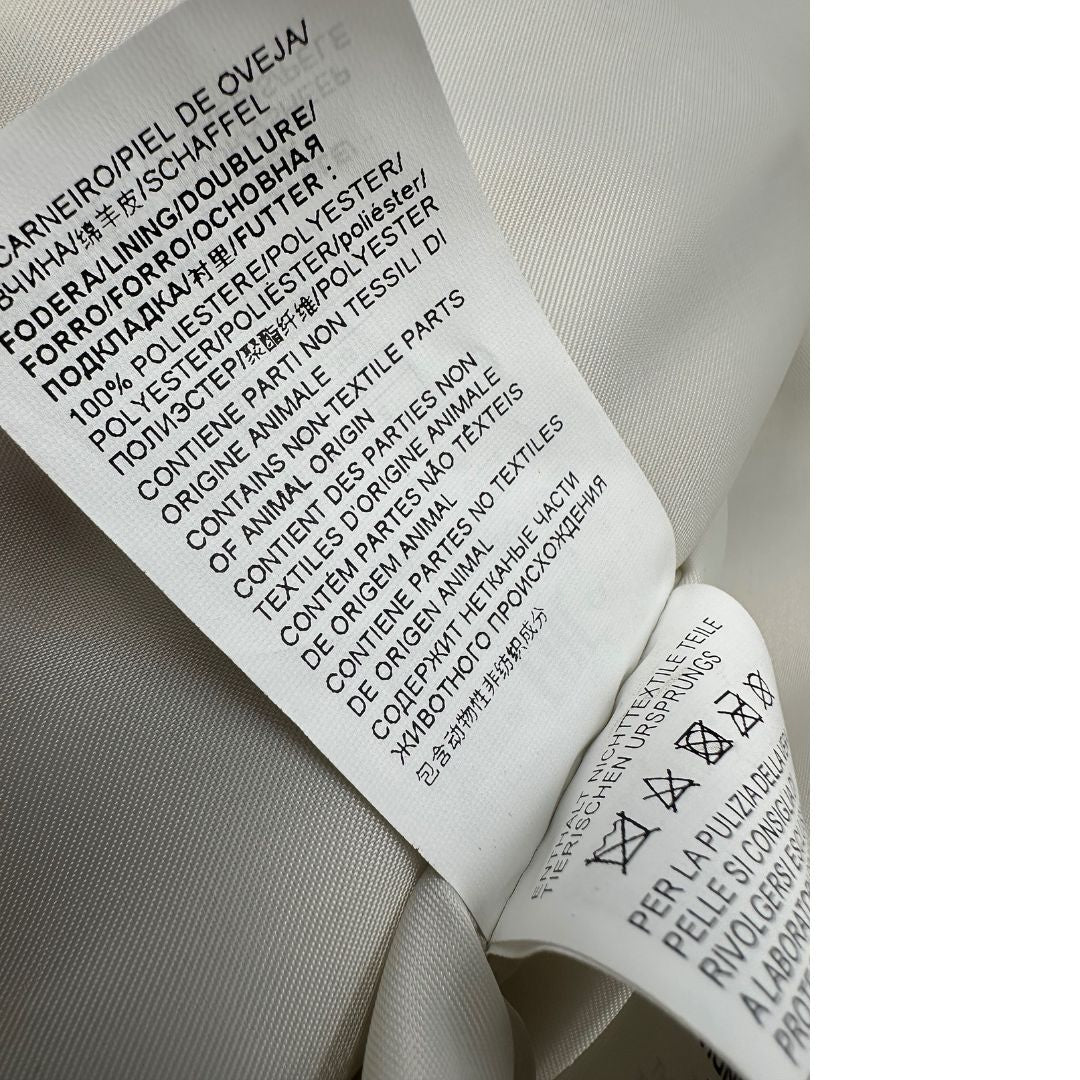Etichetta di una giacca in 100% pelle Pinko bianco latte, con parti metalliche dorate, taglia 40.