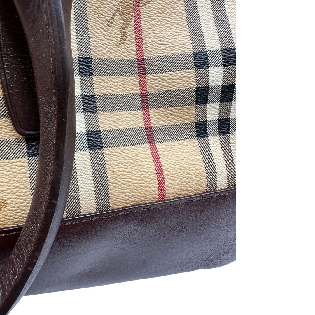 Alone sul canvas di un borsone Burberry in canvas trama tartan con finiture in pelle marrone testa di moro e parti metalliche dorate; munito di doppi manici stondati e una tracolla amovibile e regolabile.