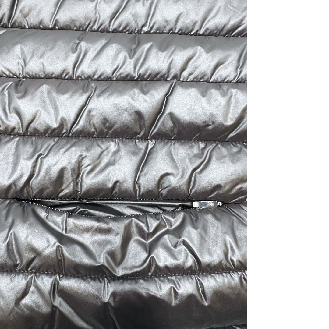 Piumino copri spalle Fay in 100% poliammide nero trapuntato con parti metalliche argentate, con chiusura elastica a gancio con barra e tasche con zip.