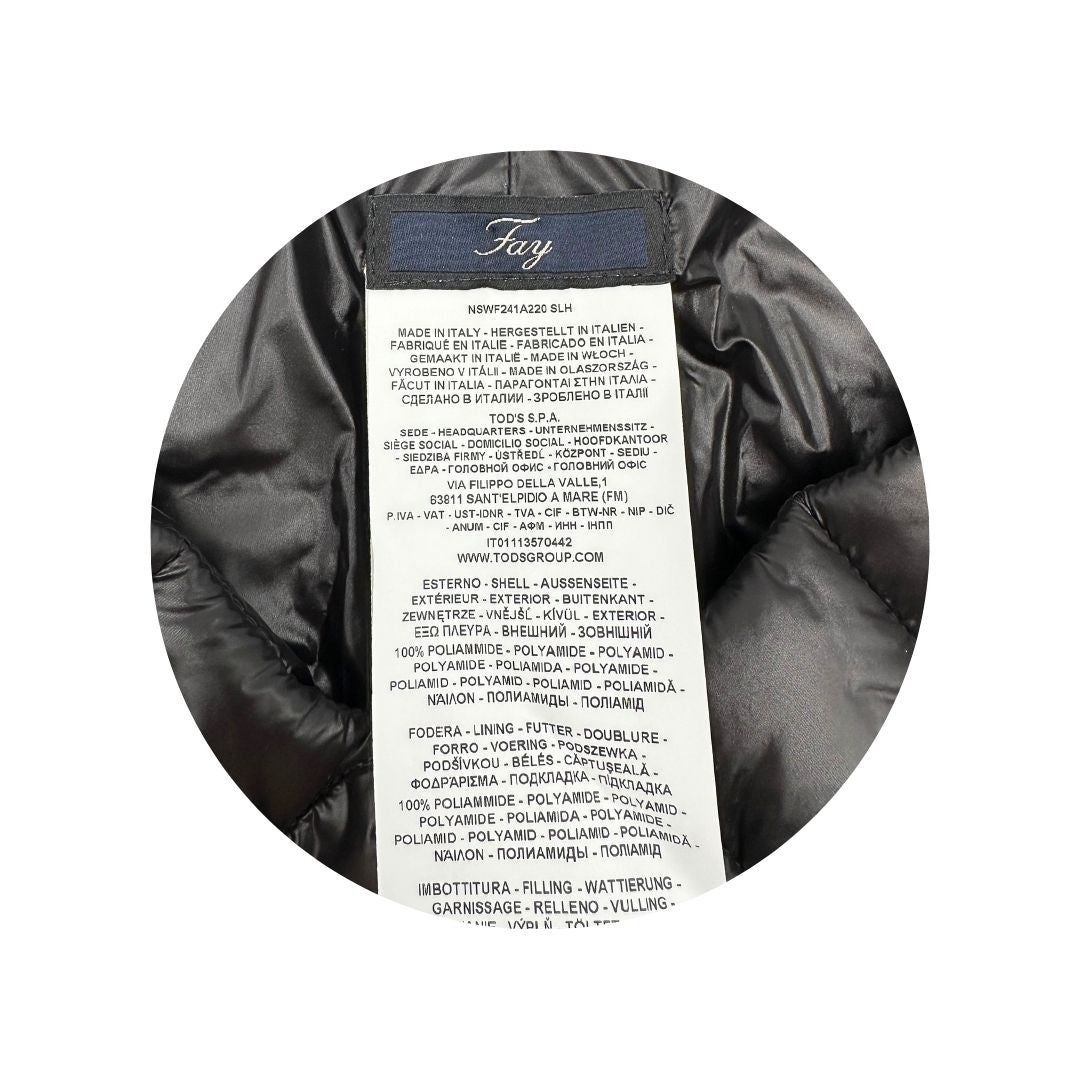 Etichetta di un piumino copri spalle Fay in 100% poliammide nero trapuntato con parti metalliche argentate, con chiusura elastica a gancio con barra e tasche con zip.