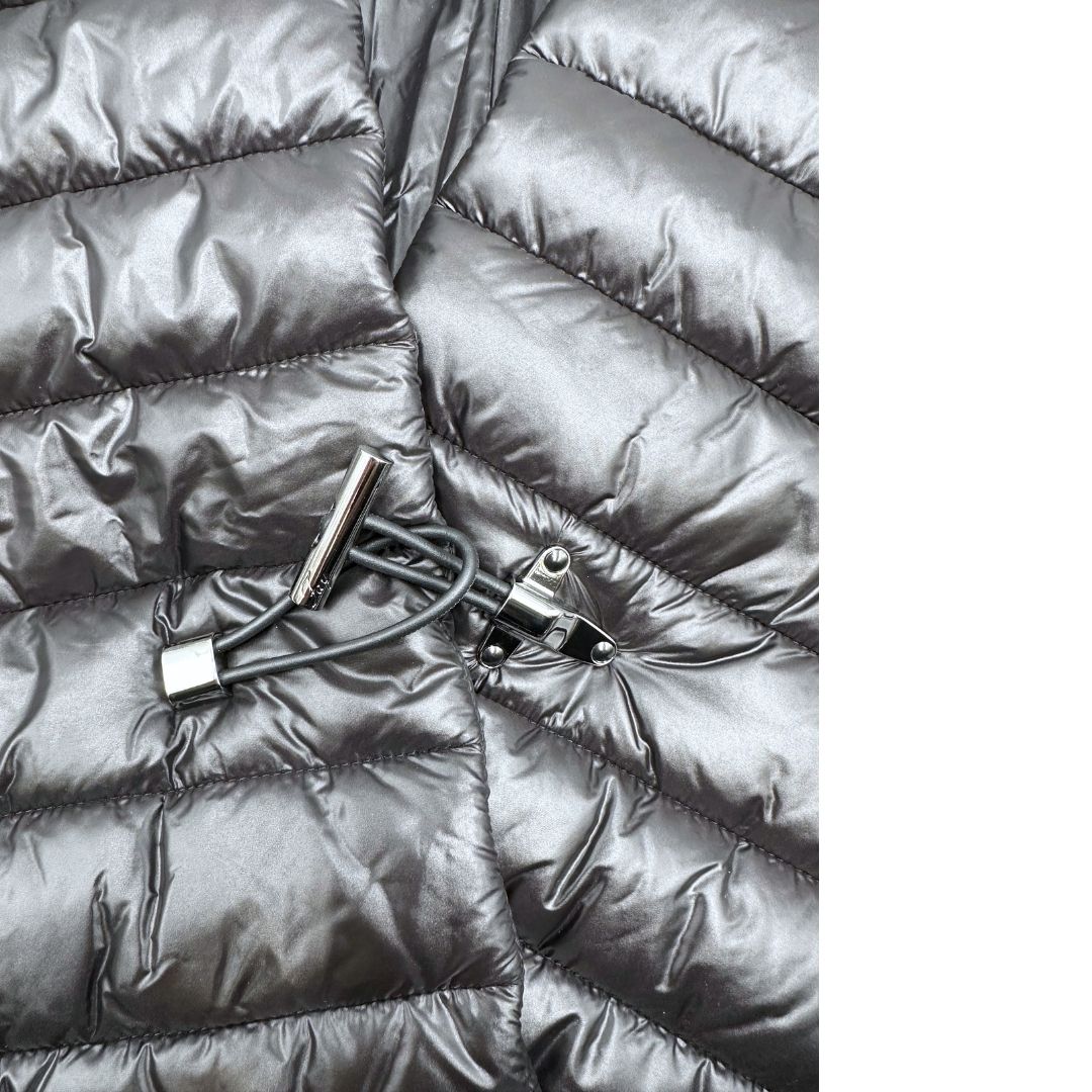 Chiusura di un piumino copri spalle Fay in 100% poliammide nero trapuntato con parti metalliche argentate, con chiusura elastica a gancio con barra e tasche con zip.