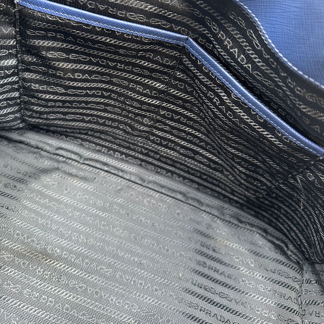 interno  della Borsa Prada in pelle saffiano blu con parti metalliche dorate; munita di doppi manici stondati e impreziosita da una clochette portachiavi, di lusso, originale, ottime condizioni, usata.