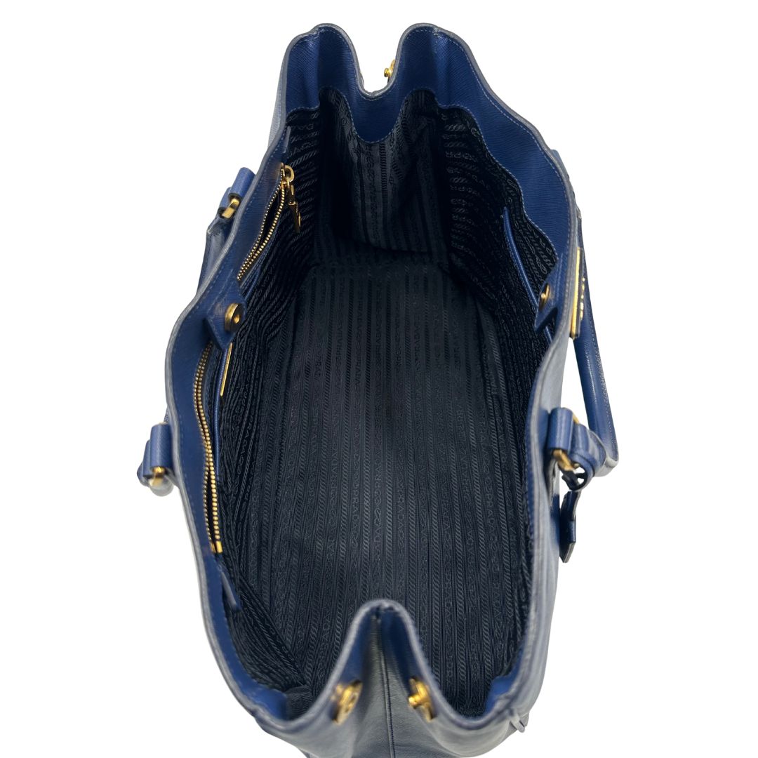 interno della Borsa Prada in pelle saffiano blu con parti metalliche dorate; munita di doppi manici stondati e impreziosita da una clochette portachiavi, di lusso, originale, ottime condizioni, usata.