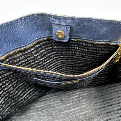 interno  della Borsa Prada in pelle saffiano blu con parti metalliche dorate; munita di doppi manici stondati e impreziosita da una clochette portachiavi, di lusso, originale, ottime condizioni, usata. 