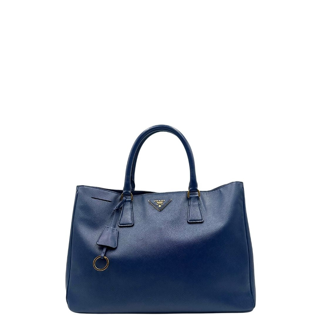 front Borsa Prada in pelle saffiano blu con parti metalliche dorate; munita di doppi manici stondati e impreziosita da una clochette portachiavi, di lusso, originale, ottime condizioni, usata. 