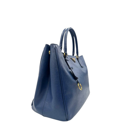 lato della Borsa Prada in pelle saffiano blu con parti metalliche dorate; munita di doppi manici stondati e impreziosita da una clochette portachiavi, di lusso, originale, ottime condizioni, usata.