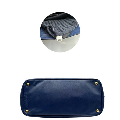 base e codice  della Borsa Prada in pelle saffiano blu con parti metalliche dorate; munita di doppi manici stondati e impreziosita da una clochette portachiavi, di lusso, originale, ottime condizioni, usata. 