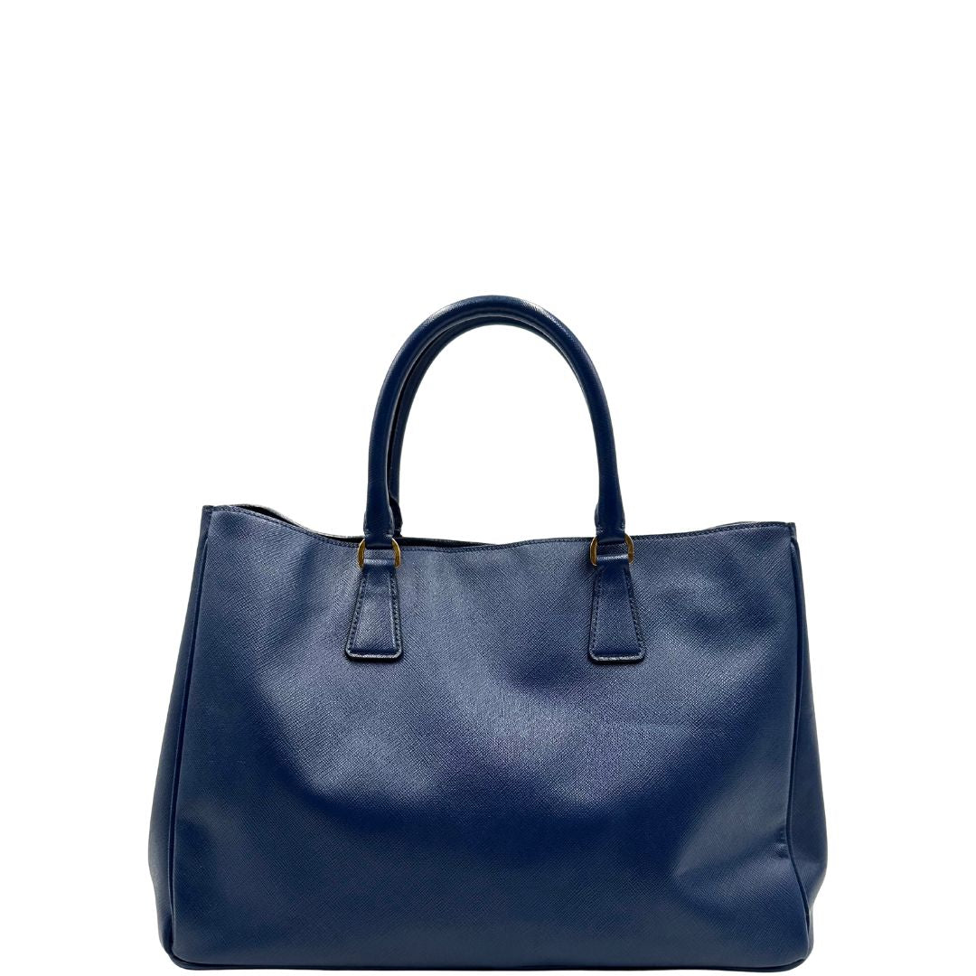 retro  della Borsa Prada in pelle saffiano blu con parti metalliche dorate; munita di doppi manici stondati e impreziosita da una clochette portachiavi, di lusso, originale, ottime condizioni, usata. 