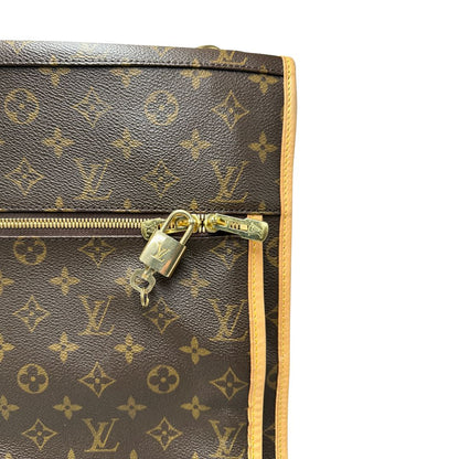 Lucchetto e chiave di una Borsa da viaggio porta abiti in canvas marrone monogram con finiture in vacchetta naturale e parti metalliche dorate; munita di un manico singolo, una tracolla amovibile e regolabile e 2 grucce. Completa di Lucchetti e una chiave, dustbag.