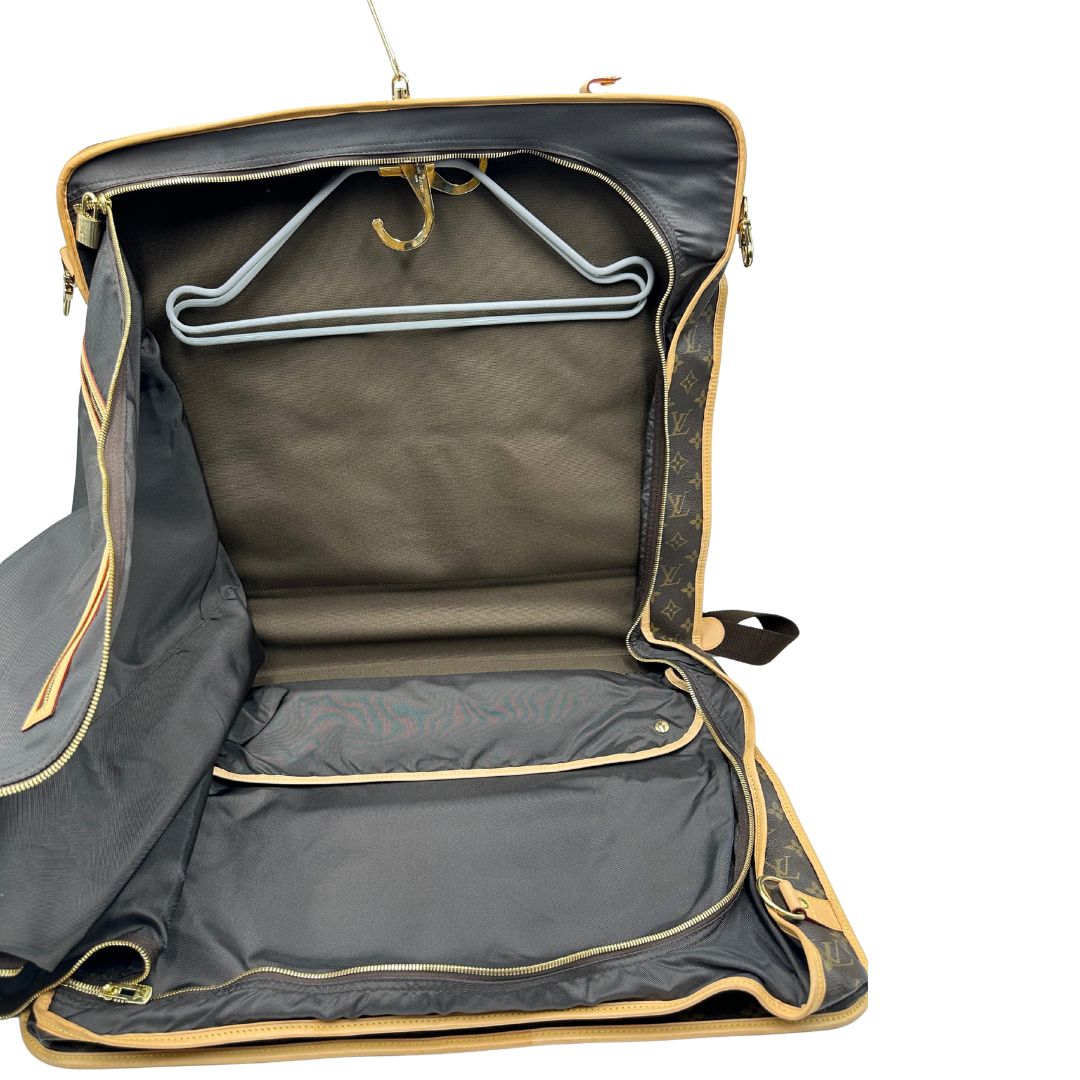 Interno di una Borsa da viaggio porta abiti in canvas marrone monogram con finiture in vacchetta naturale e parti metalliche dorate; munita di un manico singolo, una tracolla amovibile e regolabile e 2 grucce. Completa di Lucchetti e una chiave, dustbag.