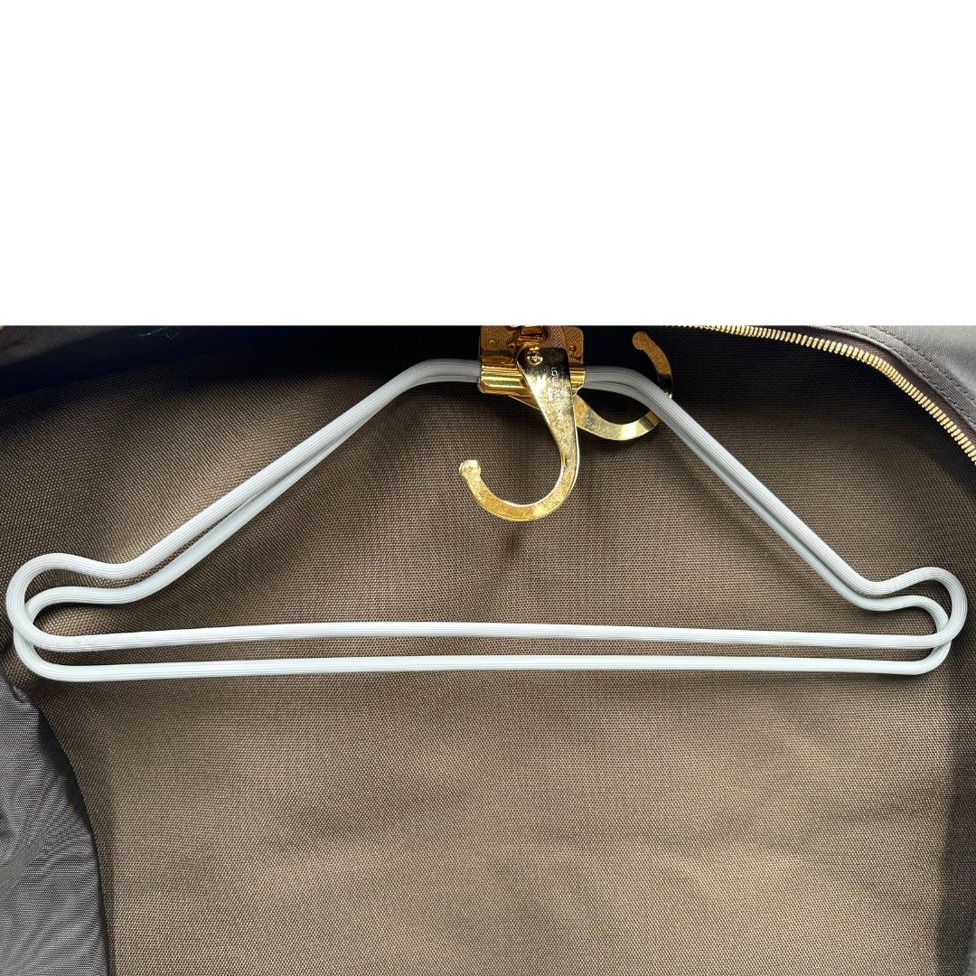 Grucce di una Borsa da viaggio porta abiti in canvas marrone monogram con finiture in vacchetta naturale e parti metalliche dorate; munita di un manico singolo, una tracolla amovibile e regolabile e 2 grucce. Completa di Lucchetti e una chiave, dustbag.