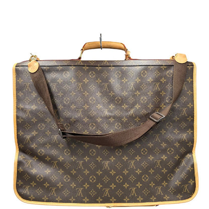 Retro una Borsa da viaggio porta abiti in canvas marrone monogram con finiture in vacchetta naturale e parti metalliche dorate; munita di un manico singolo, una tracolla amovibile e regolabile e 2 grucce. Completa di Lucchetti e una chiave, dustbag.