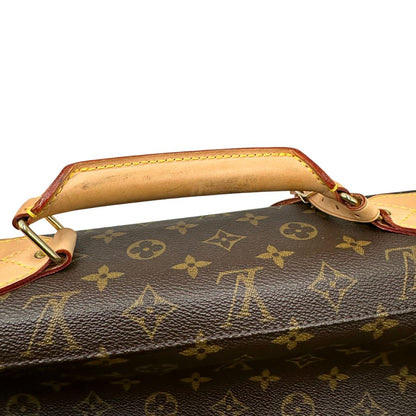 Manico di una Borsa da viaggio porta abiti in canvas marrone monogram con finiture in vacchetta naturale e parti metalliche dorate; munita di un manico singolo, una tracolla amovibile e regolabile e 2 grucce. Completa di Lucchetti e una chiave, dustbag.