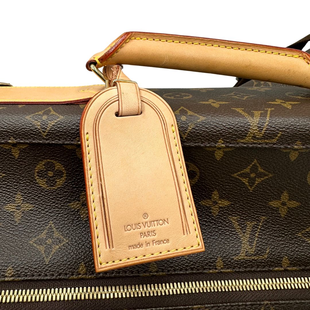 Borsa da viaggio porta abiti in canvas marrone monogram con finiture in vacchetta naturale e parti metalliche dorate; munita di un manico singolo, una tracolla amovibile e regolabile e 2 grucce. Completa di Lucchetti e una chiave, dustbag.