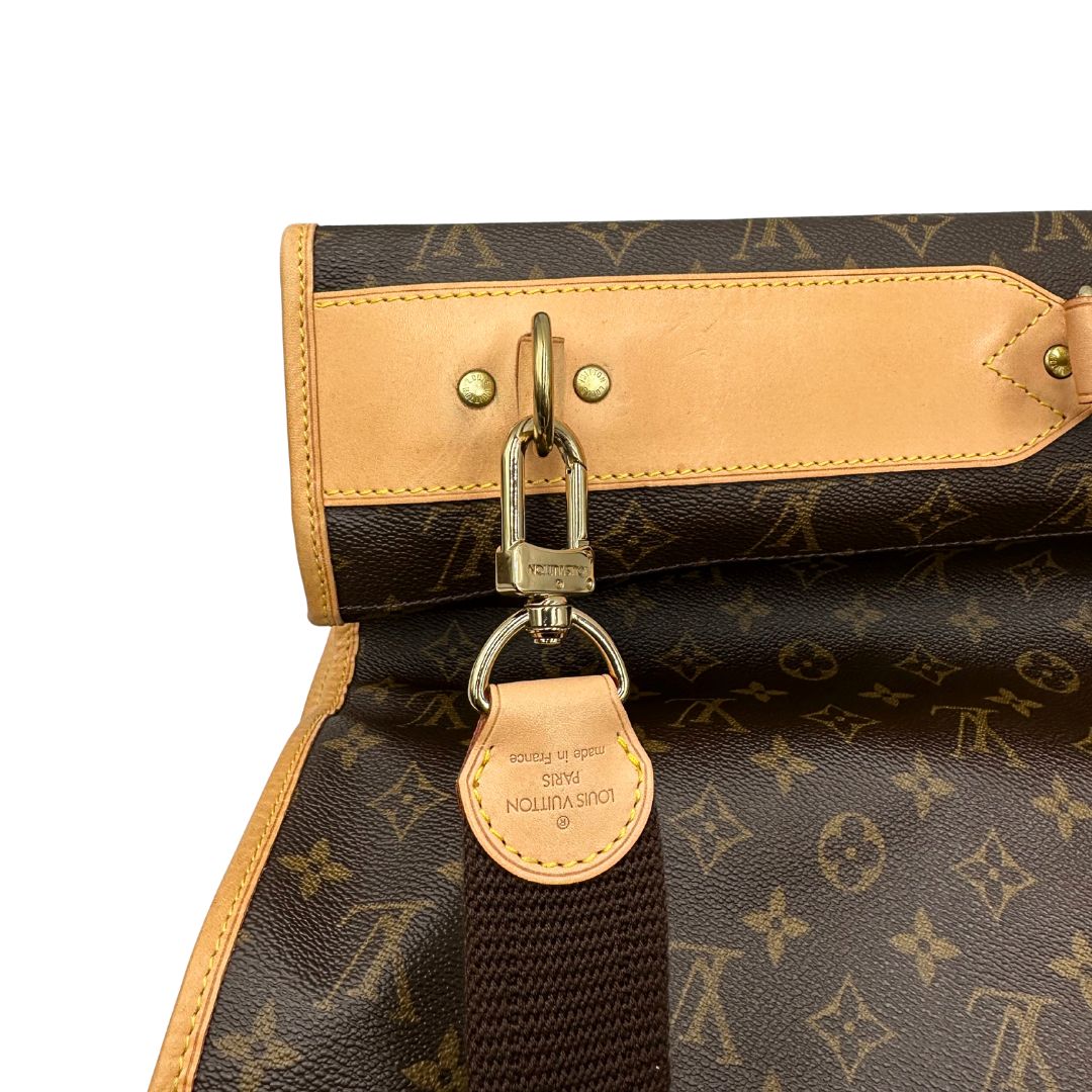 Borsa da viaggio porta abiti in canvas marrone monogram con finiture in vacchetta naturale e parti metalliche dorate; munita di un manico singolo, una tracolla amovibile e regolabile e 2 grucce. Completa di Lucchetti e una chiave, dustbag.