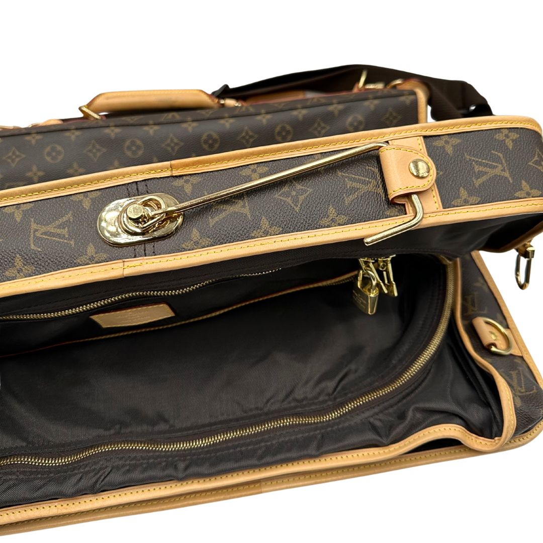 Borsa da viaggio porta abiti in canvas marrone monogram con finiture in vacchetta naturale e parti metalliche dorate; munita di un manico singolo, una tracolla amovibile e regolabile e 2 grucce. Completa di Lucchetti e una chiave, dustbag.