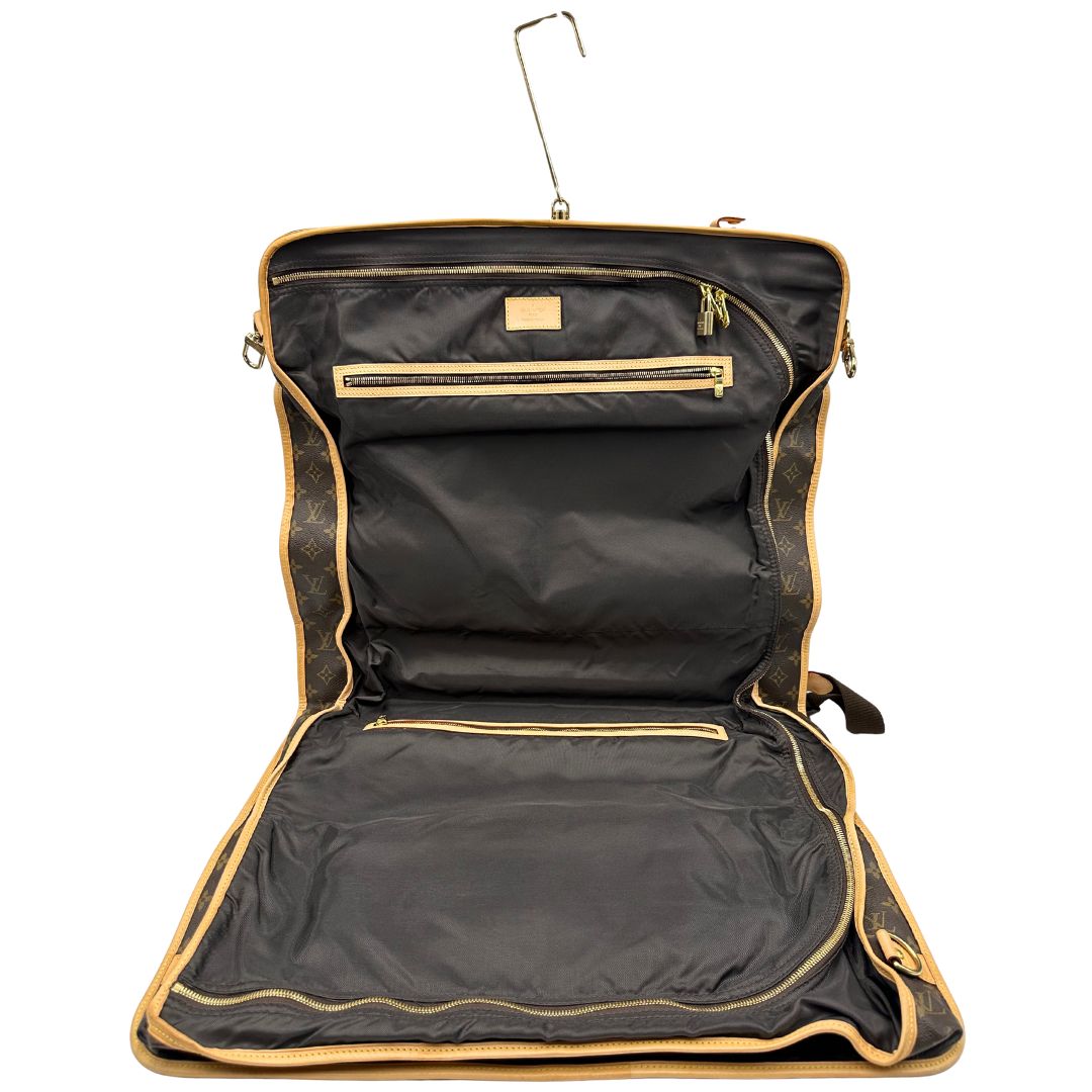 Interno di una Borsa da viaggio porta abiti in canvas marrone monogram con finiture in vacchetta naturale e parti metalliche dorate; munita di un manico singolo, una tracolla amovibile e regolabile e 2 grucce. Completa di Lucchetti e una chiave, dustbag.