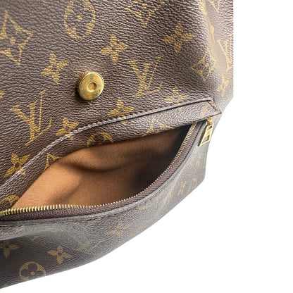 Taschino interno di uno zaino Montsouris NM in canvas marrone monogram con finiture in vacchetta naturale e parti metalliche dorate, munito di un manico sulla parte superiore e due bretelle in vacchetta regolabili. Completo di corredo e charm decorativo.
