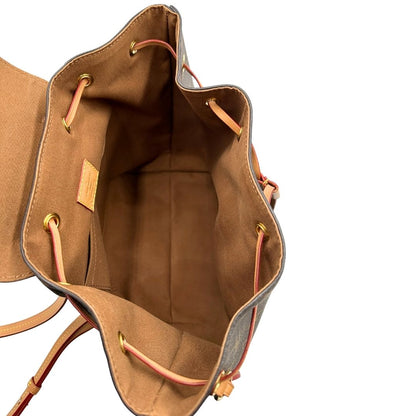 Interno di uno zaino Montsouris NM in canvas marrone monogram con finiture in vacchetta naturale e parti metalliche dorate, munito di un manico sulla parte superiore e due bretelle in vacchetta regolabili. Completo di corredo e charm decorativo.