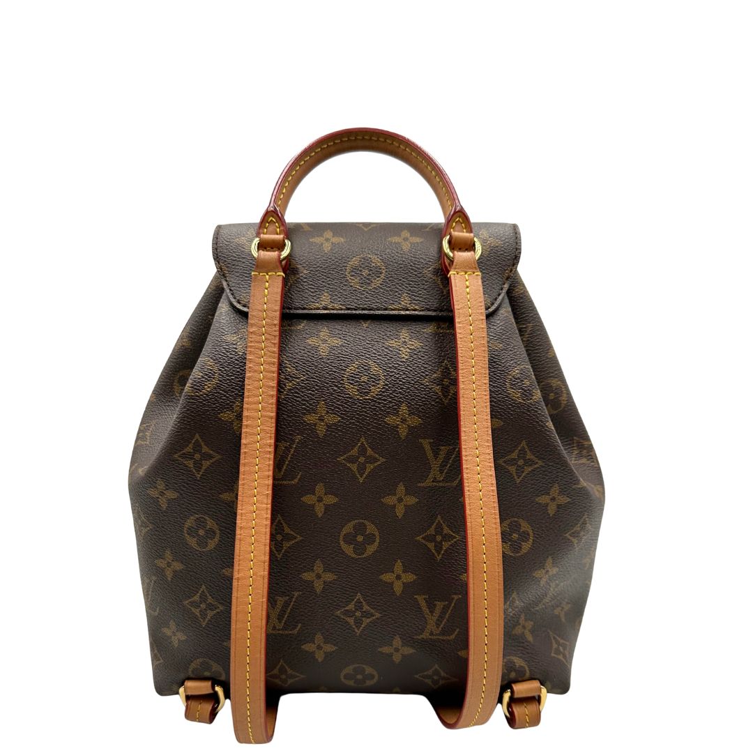 Retro di uno zaino Montsouris NM in canvas marrone monogram con finiture in vacchetta naturale e parti metalliche dorate, munito di un manico sulla parte superiore e due bretelle in vacchetta regolabili. Completo di corredo e charm decorativo.