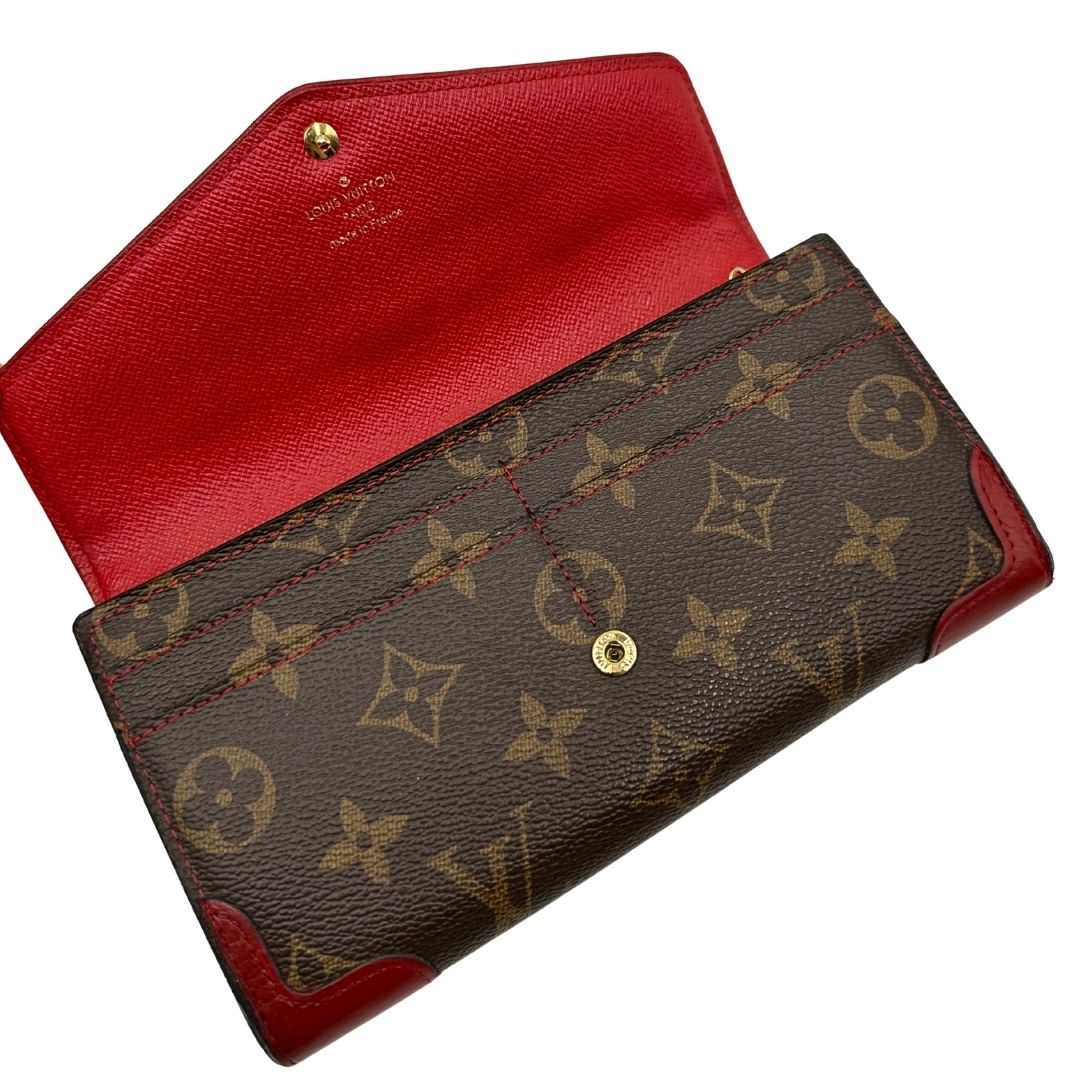Portafoglio Louis Vuitton Sarah Retiro in canvas monogrammato marrone e finiture rosse, completo di corredo.