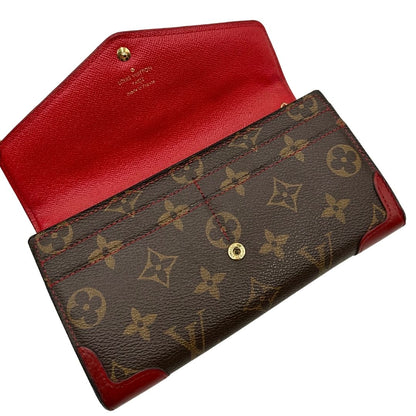 Portafoglio Louis Vuitton Sarah Retiro in canvas monogrammato marrone e finiture rosse, completo di corredo.