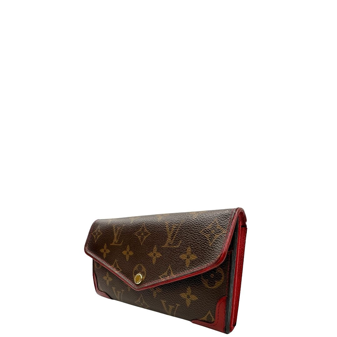 Portafoglio Louis Vuitton Sarah Retiro in canvas monogrammato marrone e finiture rosse, completo di corredo.