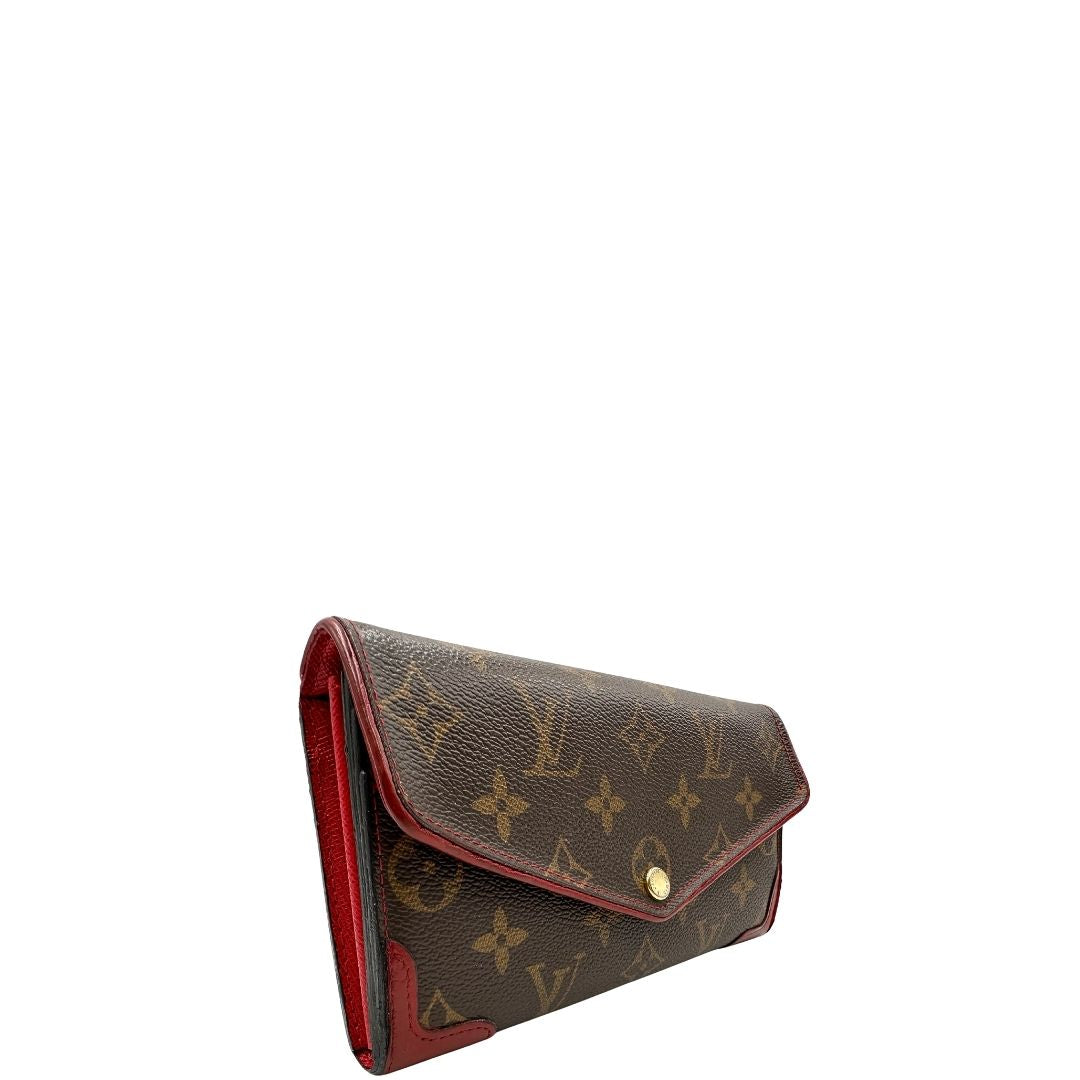 Portafoglio Louis Vuitton Sarah Retiro in canvas monogrammato marrone e finiture rosse, completo di corredo.
